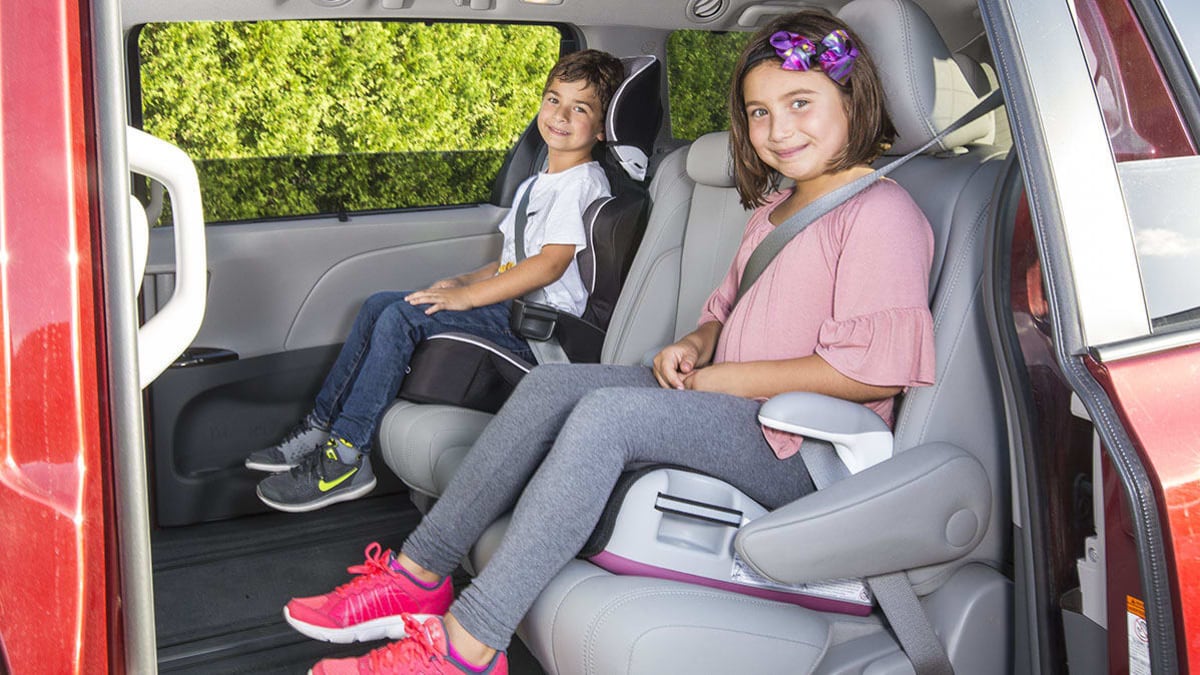 A boy and a girl seated in their booster seats.